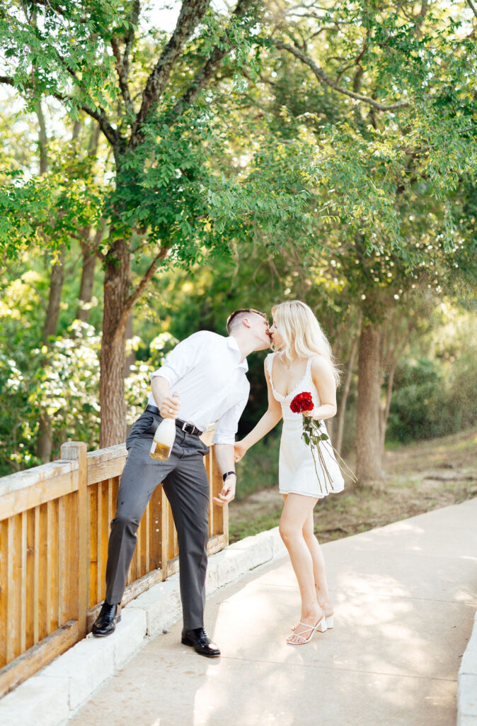 newly engaged couple opening a bottle of champagne