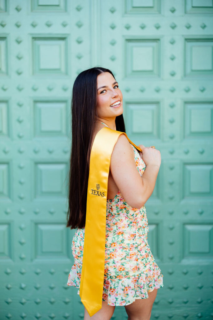 girl taking photos for college graduation in front of blue door in texas